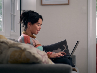 UNE student studies on a laptop on her lounge at home