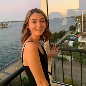 Bachelor of Criminology/Bachelor of Laws student Morgan Robins smiles on balcony with harbour behind