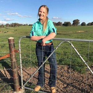 Bachelor of Rural Science graduate Sara Paton leans over a gate on a sunny day on a rural property
