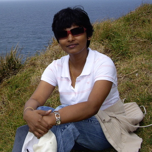 UNE PhD (Economics) graduate Dr Wasanthi Thenuwara sits on a grassy clifftop by the sea