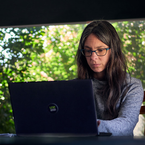 UNE graduate Amanda Williams types on her laptop at home