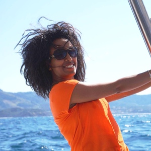 UNE student smiles in an orange shirt on a boat