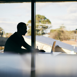 UNE student in silhouette studies by window