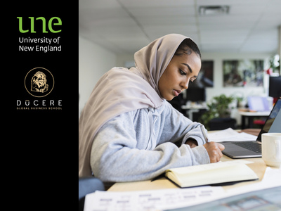 UNE student studies at library with Ducere logo