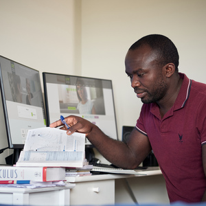 UNE student studies on computer and laptop in at desk.