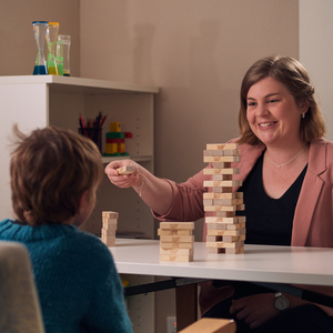 Psychologist and child sit on opposite sides of table and work together on block activity