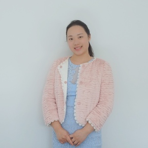 UNE planning graduate in pink jacket and blue dress smiles to camera