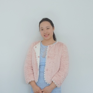 UNE graduate Shili Wang poses in front of a white wall