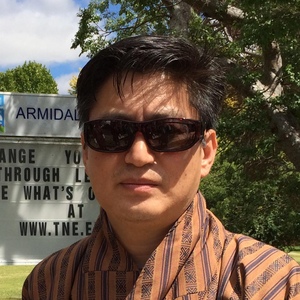 UNE graduate poses in sunglasses in front of sign