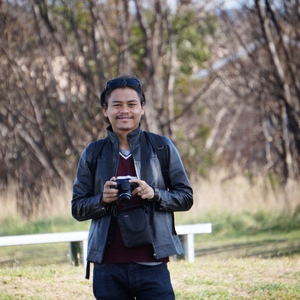 UNE graduate poses on campus with camera 