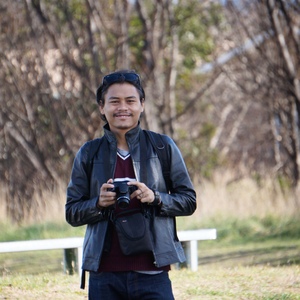 UNE graduate poses on campus with camera